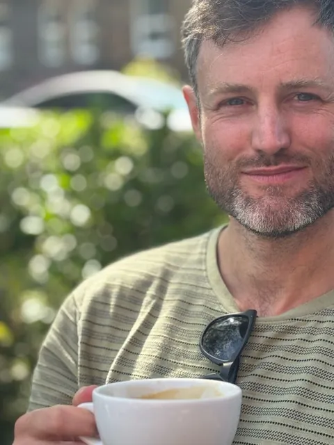 Vincent met een kop koffie, in de zon